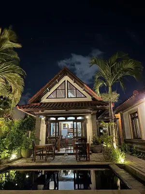a house with a table and chairs next to a pool at Bali Stuti Jimbaran Inn in Jimbaran
