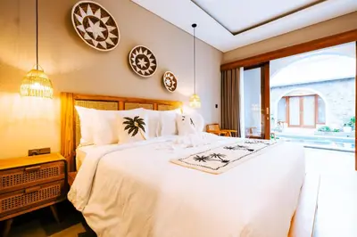 a bedroom with a large white bed and a window at Villa Koura Kuta in Kuta