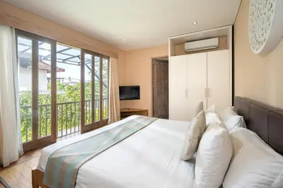 a bedroom with a large white bed and a balcony at Villa Ewa 1 in Seminyak