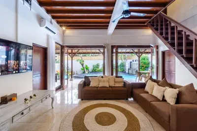 a living room with two couches and a staircase at Villa Simara in Seminyak