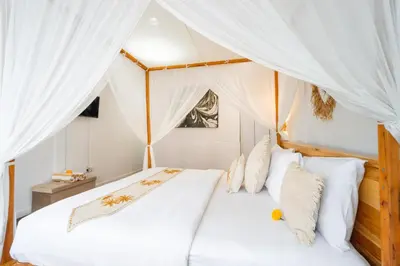 a bedroom with a canopy bed with white sheets and pillows at Villa Putri Mila in Seminyak