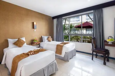 a hotel room with two beds and a window at The Kanjeng Suites Kuta Galeria - Bali in Kuta