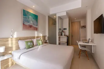 a bedroom with a large white bed and a desk at Bali Bustle Pararaton Coliving and Coworking Space in Legian