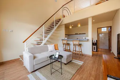 a living room with a couch and a staircase at Cove Lotus Lofts Seminyak in Seminyak