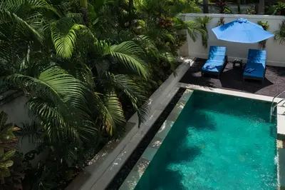 an infinity pool with two chairs and an umbrella at Classic tropical villa with private pool in Umalas in Dalung