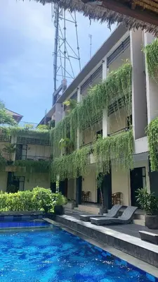 a hotel with a swimming pool in front of a building at Mansu Hotel and Spa Legian in Kuta