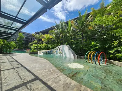a pool with a water slide in a resort at de' Asasta Apartment Benoa N508 in Nusa Dua