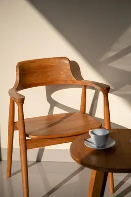 a wooden chair with a cup on a table at Titeng Guest House - Comfortable studio in amazing location near Potato Head and the beach in Seminyak