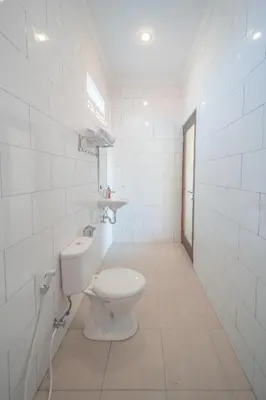 a white bathroom with a toilet and a sink at Titeng Guest House - Comfortable studio in amazing location near Potato Head and the beach in Seminyak