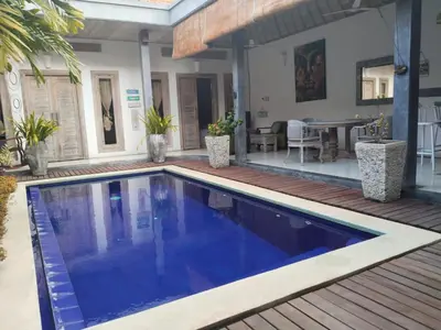 a swimming pool in a backyard with a wooden deck at JOJOBY sunset villa in Seminyak
