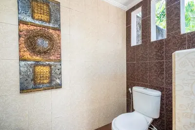 a bathroom with a toilet and a painting on the wall at Zen Villas by iBali Management in Kerobokan