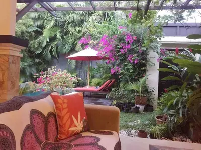 a patio with a couch and an umbrella and flowers at Seminyak Beach Villa Ashira SUPERB Location in Seminyak