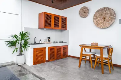 a kitchen with wooden cabinets and a table and a plant at Villa Felicia Canggu By Moria in Canggu