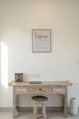 a wooden desk with a stool and a picture on the wall at Serai Villa by Betterplace in Seminyak