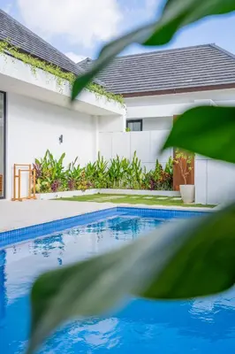 a house with a swimming pool in front of a house at Serai Villa by Betterplace in Seminyak
