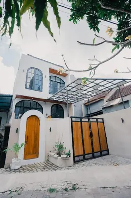 a white house with two wooden doors at Sari Buana Villa Nusa Dua in Nusa Dua