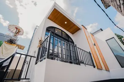 a white house with a balcony and a wooden door at Sari Buana Villa Nusa Dua in Nusa Dua