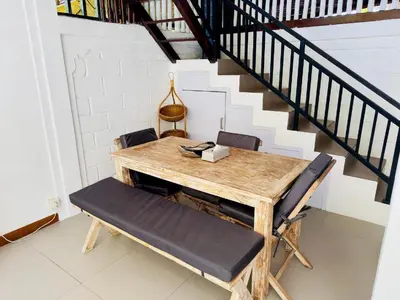 a wooden table and chairs in a room with a staircase at Tiga Kelapa Villa by Smart Digital in Legian