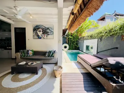 a patio with a couch and a swimming pool at Tiga Kelapa Villa by Smart Digital in Legian