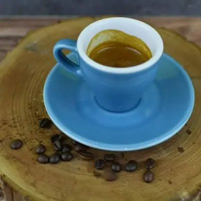 a cup of coffee on a plate with coffee beans at 9 Residences Seminyak in Seminyak