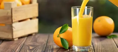 a glass of orange juice sitting on a wooden table with oranges at 9 Residences Seminyak in Seminyak