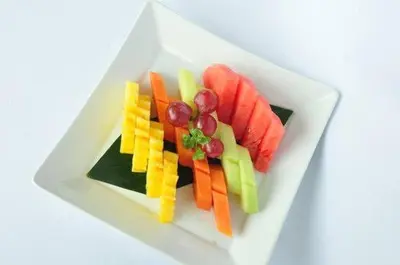 a plate of fruit and vegetables on a white plate at 9 Residences Seminyak in Seminyak