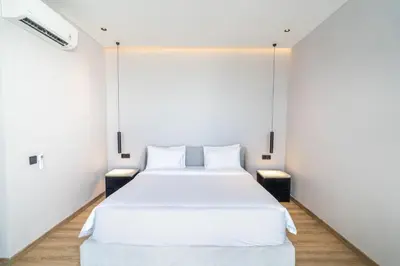 a bedroom with a large white bed with white walls at Luxury Haven Stunning 2Br in Umalas Canggu in Kerobokan