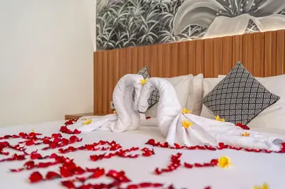 a bed with towels and red flowers on it at Umasuka Villa in Denpasar