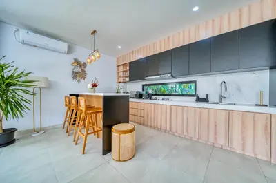 a kitchen with black cabinets and a bar with stools at Villa Kangla - 3BR Luxurious Villa Seminyak in Seminyak
