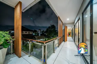 a balcony with glass walls and a view of the city at SOHO Seminyak 1 - by Unicorn Villas Bali in Seminyak