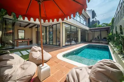 a house with a swimming pool and an umbrella at Villa Casa Del Sol Umalas in Kerobokan