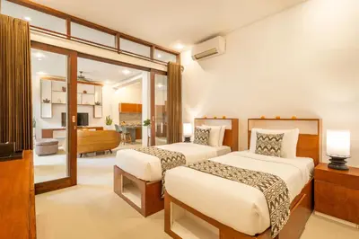 a bedroom with two beds and a living room at Seven Residence in Seminyak