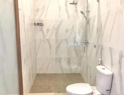 a white bathroom with a shower and a toilet at Surya Homestay in Seminyak