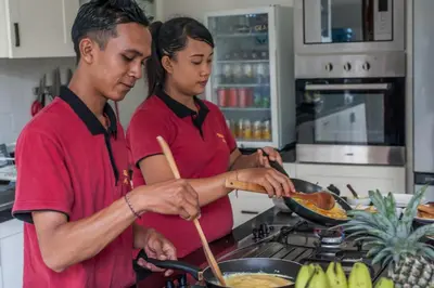 a man and woman preparing food in a kitchen at Villa Annecy in Seminyak