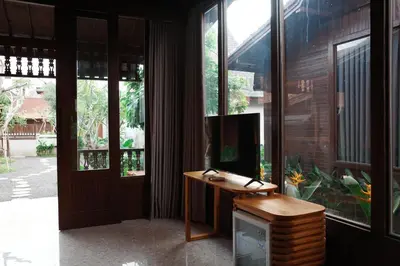 a room with a desk with a television and large windows at The Riang Villa in Kerobokan