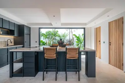 an open kitchen with a large island with two bar stools at Villa Moana - Incredible 2BR Villa Next To The Beach in Canggu in Canggu