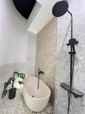 a bathroom with a bath tub and a plant at Della Rossa in Seminyak