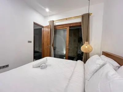 a bedroom with a white bed with a clock on it at Della Rossa in Seminyak