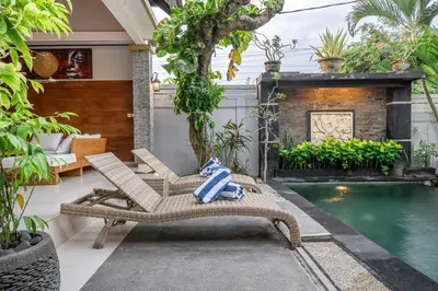 a patio with two chairs and a swimming pool at QLO Villa , Seminyak in Seminyak