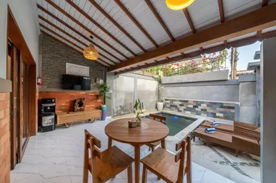 a patio with a table and chairs and a pool at Q LA Villas in Seminyak