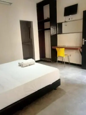 a bedroom with a bed and a yellow chair at Vico hotel in Nusa Dua