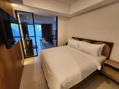 a bedroom with a white bed and a balcony at de' Asasta Apartment Benoa E216 in Nusa Dua