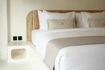 a white bed with white sheets and pillows at Armonia Bali Legian Villas in Legian
