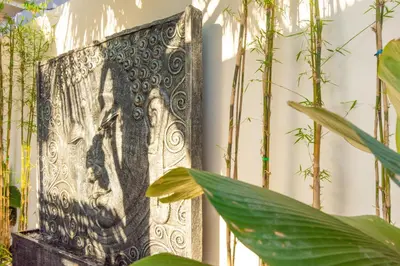a metal picture of a woman on a wall with plants at Villa Mayo in Legian