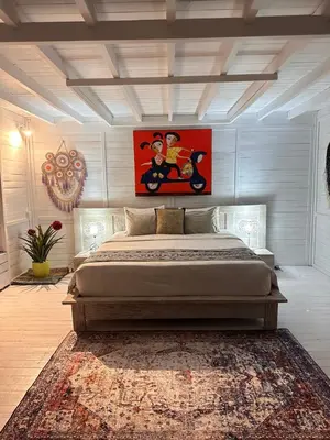 a bedroom with a large bed with a painting on the wall at Kenzo hut3 mesari in Seminyak