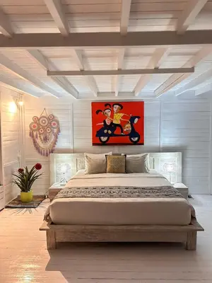 a bedroom with a large bed with a painting on the wall at Kenzo hut3 mesari in Seminyak