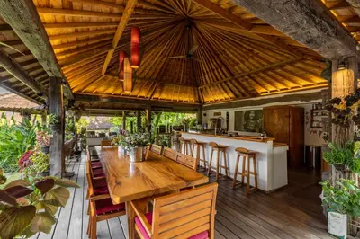a dining room with a wooden table and a bar at Villa Tago - 5 BR Villa in Umalas in Kerobokan