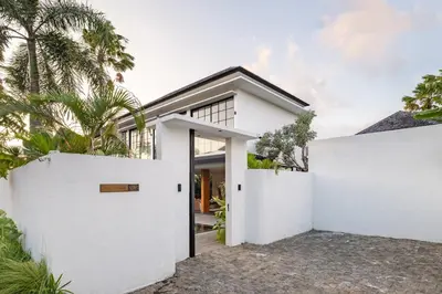 a house with white walls and palm trees at The Fernweh Umalas in Canggu