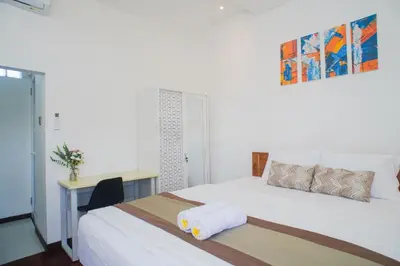 a bedroom with two beds and a desk with a desk at Fun Living Guest House in Seminyak