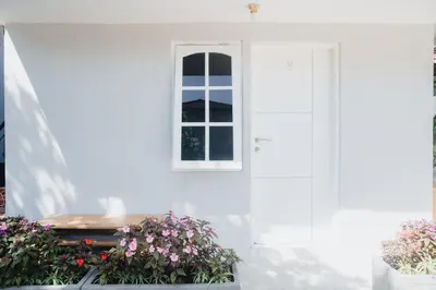 a white house with a window and some flowers at Fun Living Guest House in Seminyak